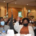 Diocesan Convention members raise "Aye" voting cards to create a Reparations Fund